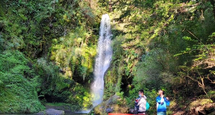 Des gens prennent des photos devant une cascade.