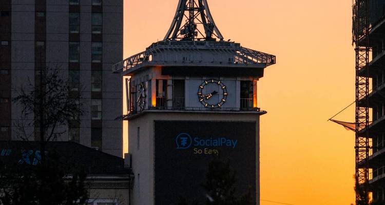 Una torre de reloj de la ciudad al atardecer con un logotipo prominente.