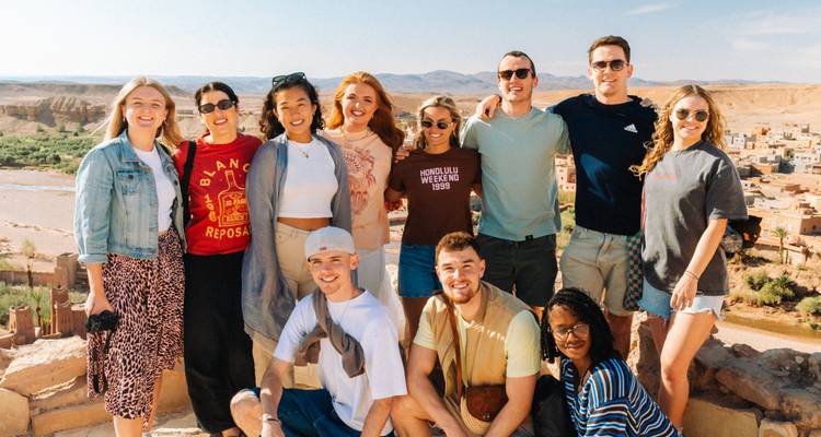 Grupo de turistas posando con un pueblo marroquí de fondo.