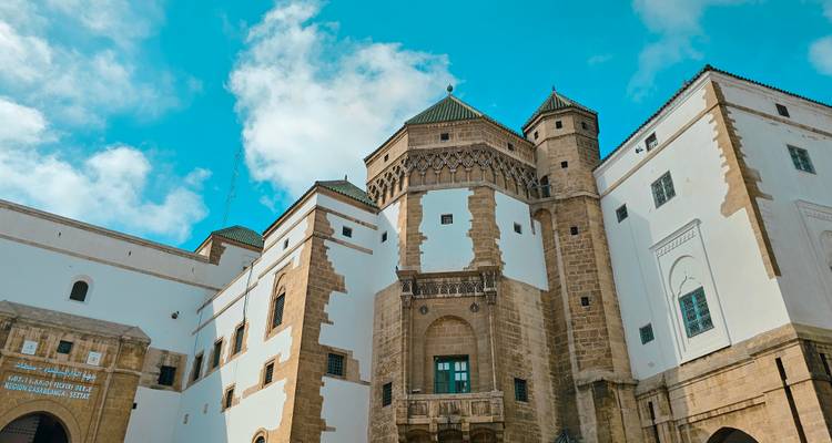 Un edificio histórico con diseño tradicional marroquí bajo un cielo azul brillante.