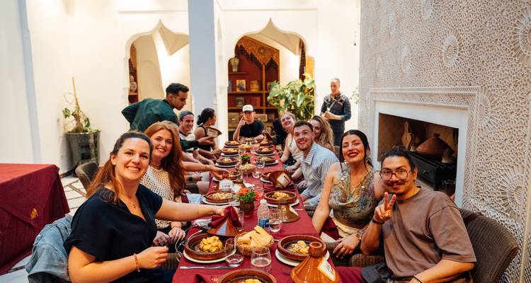 Un grupo de personas disfrutando de una comida tradicional en una mesa larga en un entorno opulento.