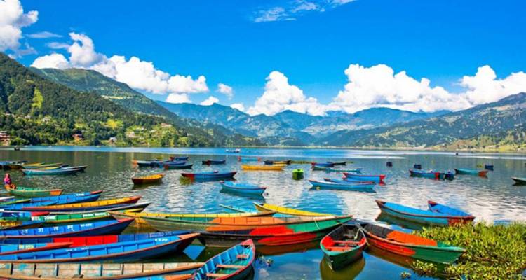 Kleurrijke boten op een meer met heuvels op de achtergrond.