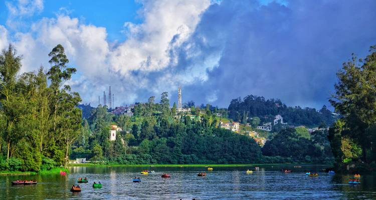Lago con botes de pedales coloridos y edificios en la orilla.