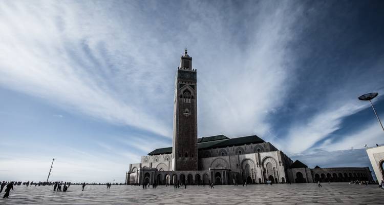 Zicht op een grote moskee met een hoge minaret onder een dramatische lucht.