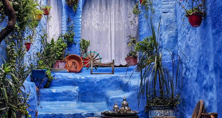 Blau gestrichene Stufen mit Pflanzen und traditionellen marokkanischen Gegenständen.