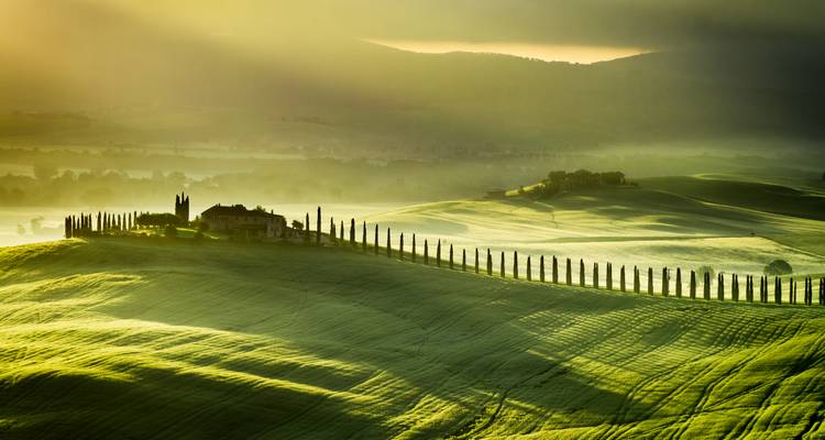 Resplandor dorado sobre los campos de la Toscana con una granja.