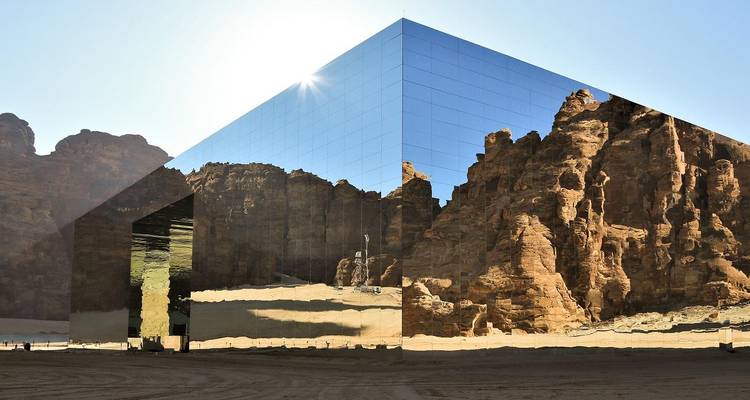Edificio gigante con espejos que refleja el paisaje desértico circundante.