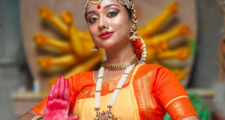 Une femme en tenue de danse indienne traditionnelle, posant avec un geste gracieux de la main.