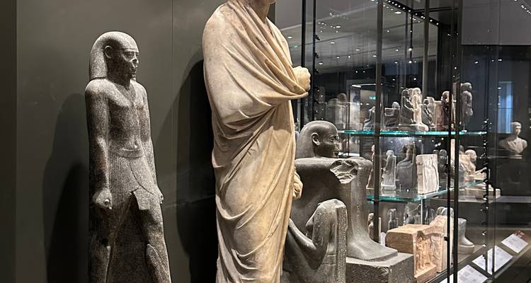 Estatuas antiguas y artefactos exhibidos en un museo moderno.