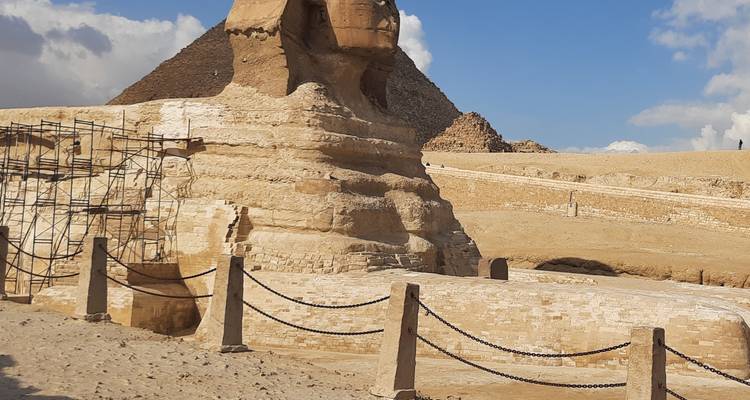 Vista lateral de la Esfinge con una pirámide al fondo.