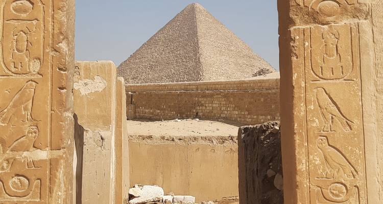 Pirámide vista a través de un arco de piedra antigua con jeroglíficos.