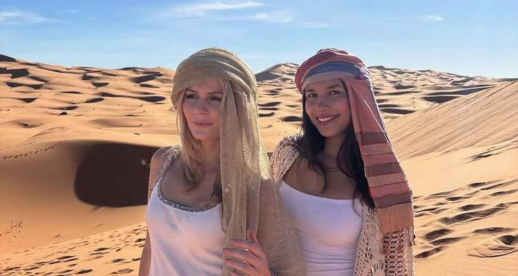 Dos personas usando bufandas tradicionales en un desierto.