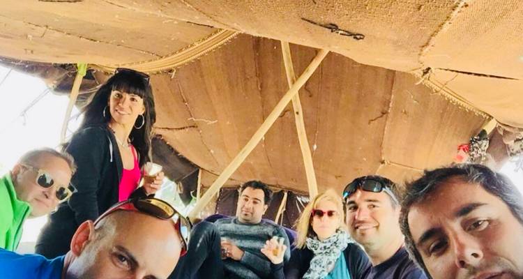 Grupo de personas dentro de una tienda de campaña, disfrutando de una bebida.