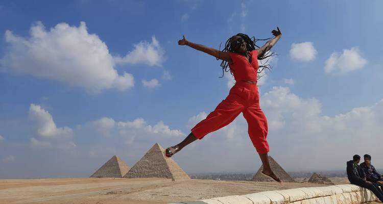 Personne sautant joyeusement devant des pyramides.