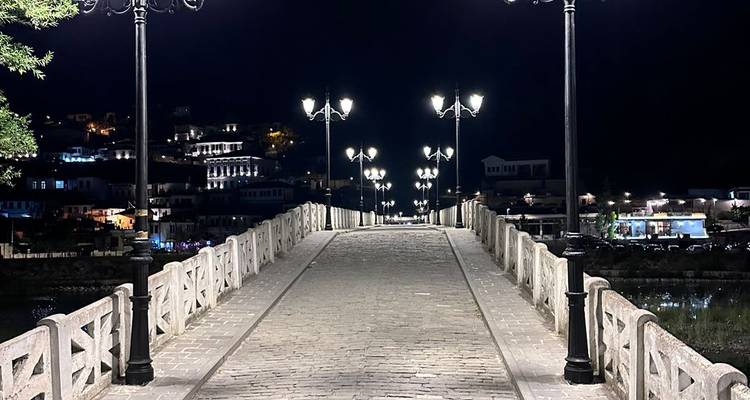 Sendero de puente iluminado en un pueblo por la noche.
