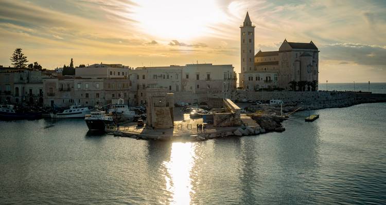 Middeleeuwse kuststad bij zonsondergang met boten in de haven
