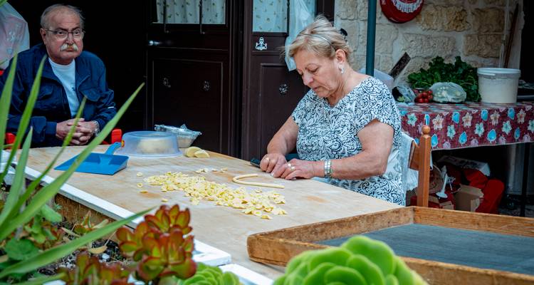 Vrouw die traditionele pasta maakt met een man die in de buurt zit