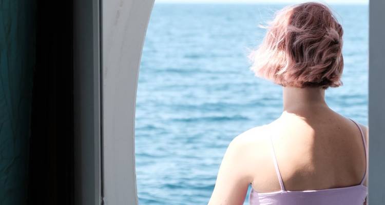 Personne regardant vers la mer depuis la fenêtre d'un bateau.