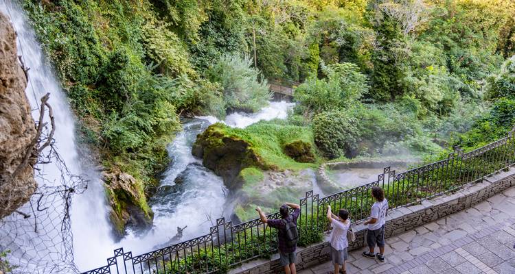 Visitantes observando una exuberante cascada rodeada de vegetación.