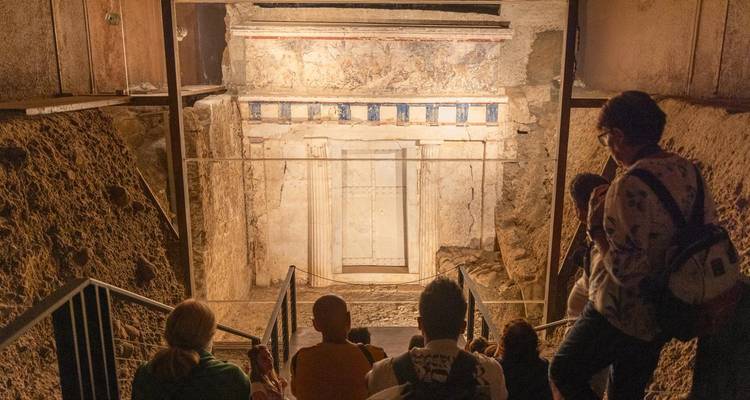 Visitantes observando la entrada de una tumba antigua elaboradamente decorada.