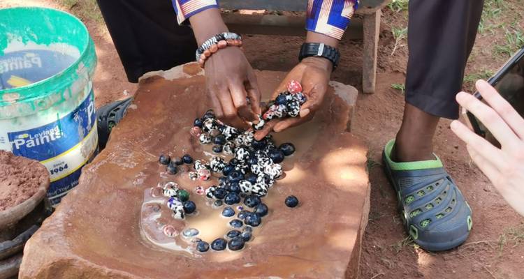 Persona manipulando cuentas coloridas en un entorno tradicional.
