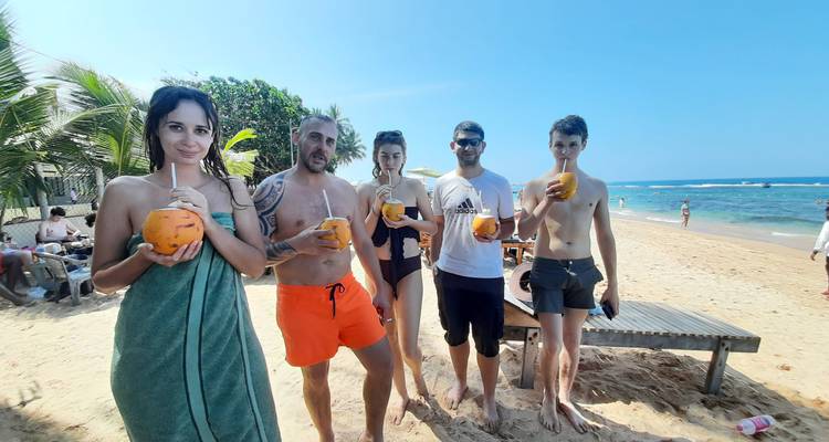 Groupe de personnes savourant des noix de coco sur la plage.