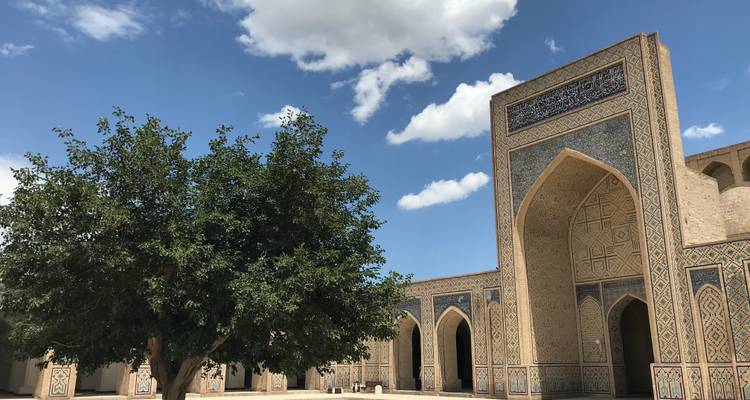 Großer Innenhof mit kunstvoller Fliesenarbeit und einem zentralen Baum.