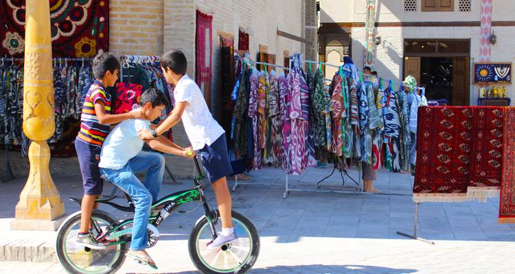 Kinder, die in einer bunten Marktstraße auf einem Fahrrad spielen.