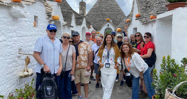 Gruppe von Touristen in einer malerischen Stadt mit Trulli-Häusern.