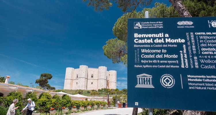 Panneau d'interprétation accueillant les visiteurs au Castel del Monte avec la forteresse médiévale visible en arrière-plan.