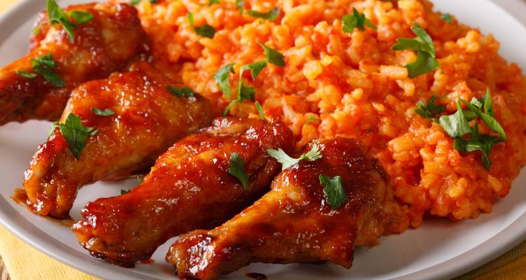 Close-up van pittige rijst en kippenvleugels gegarneerd met kruiden.