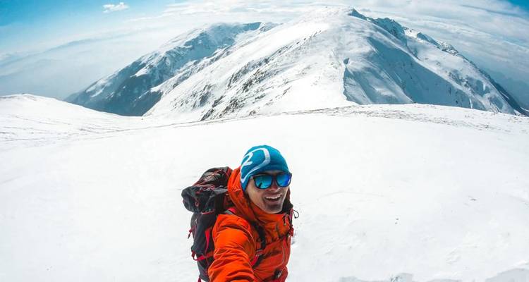 Persona tomándose una selfie en un paisaje montañoso nevado.