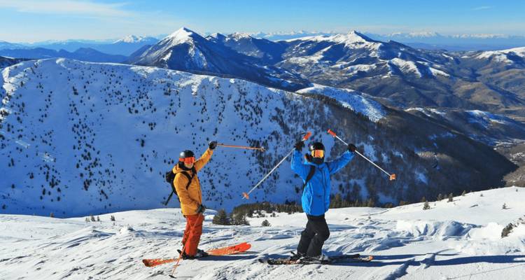 Dos esquiadores en una montaña nevada haciendo gestos con entusiasmo.