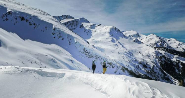 Dos personas de pie en una montaña nevada con vistas panorámicas.