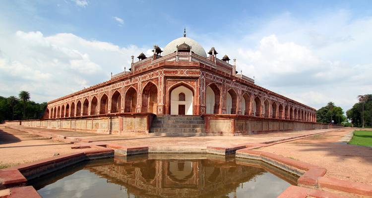 Palacio simétrico con una piscina al frente, cielos despejados.