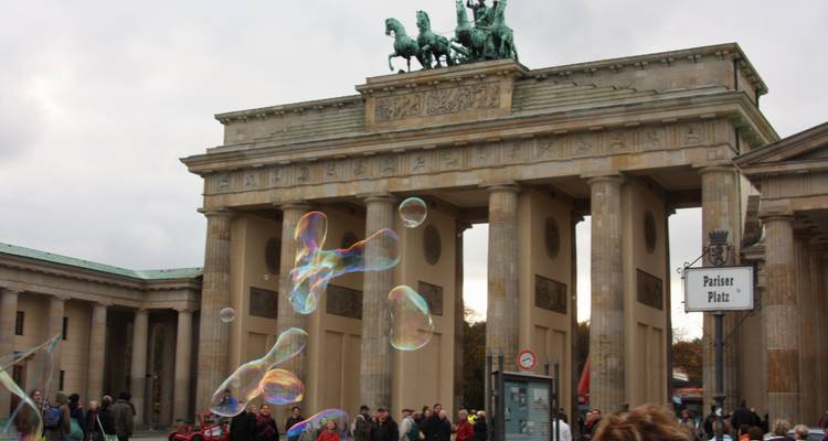 The Brandenburg Gate with people and bubbles in the air.