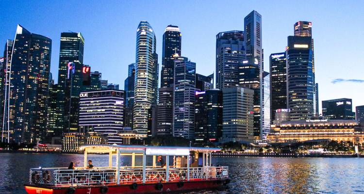 Vista de un ferry en el agua con el horizonte de Singapur de fondo.