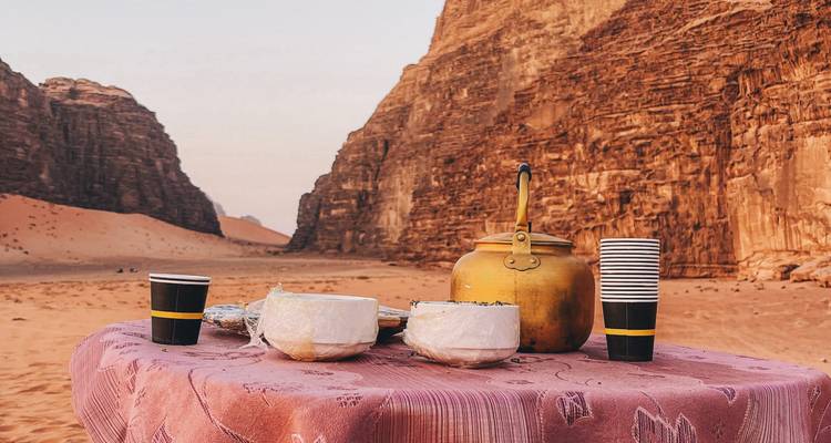 Simple table set with teapot, bowls and cups amid towering sandstone walls of the desert canyon.