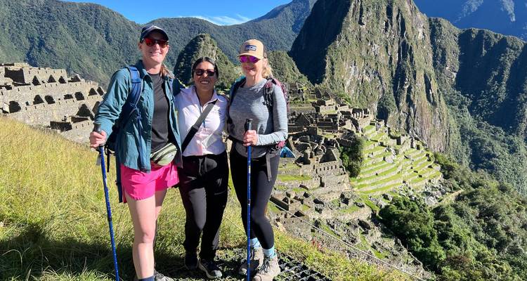 Tres excursionistas posando con las ruinas de Machu Picchu de fondo.