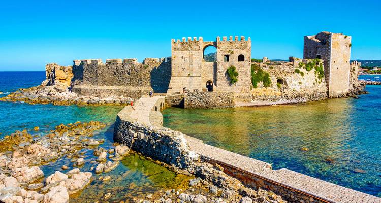 Antigua fortaleza de piedra sobre agua azul cristalina.