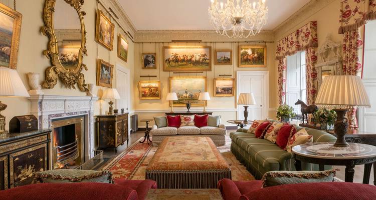 Sala de estar lujosa con muebles antiguos y pinturas.