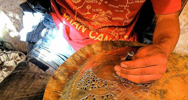 Ein Handwerker, der kunstvolle Muster in eine Metallplatte graviert.