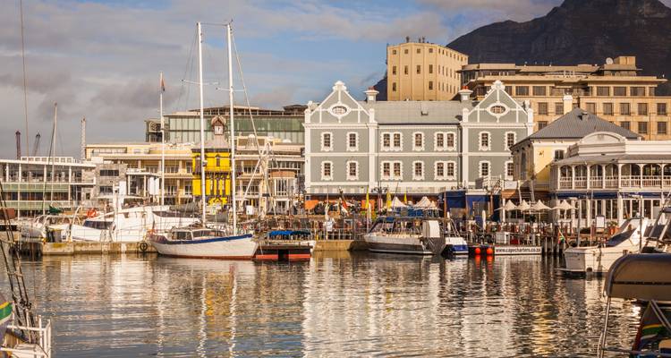 Kleurrijke historische gebouwen en boten weerspiegeld in het kalme water van de V&A Waterfront haven van Kaapstad.