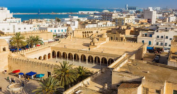 Vista aérea de un patio histórico y paisaje urbano junto al mar.