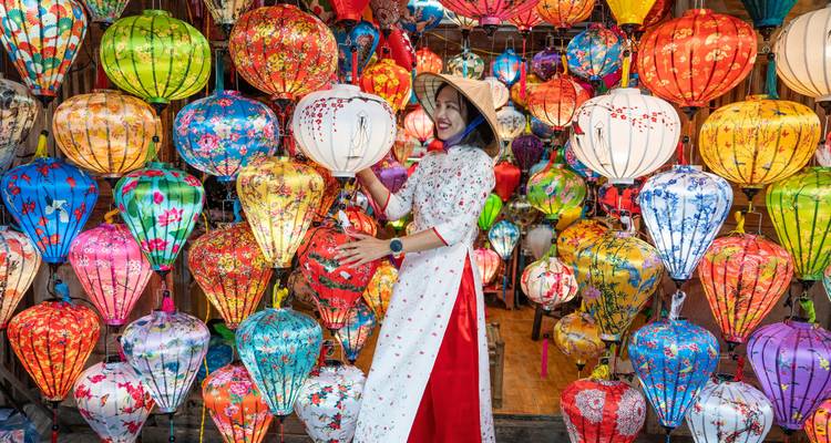 Une femme en tenue traditionnelle entourée de lanternes colorées.