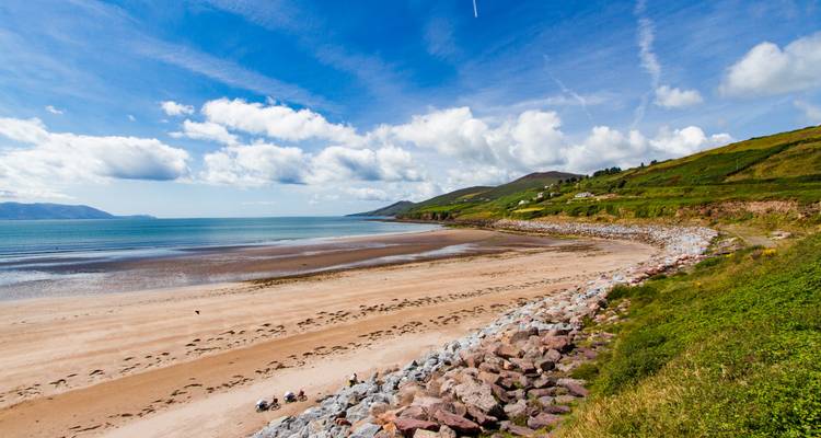 Ein langer Sandstrand mit Klippen und blauem Himmel.