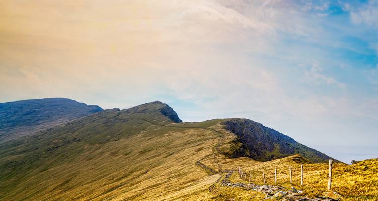Ein Panoramablick auf sanfte Hügel unter einem farbenfrohen Himmel.