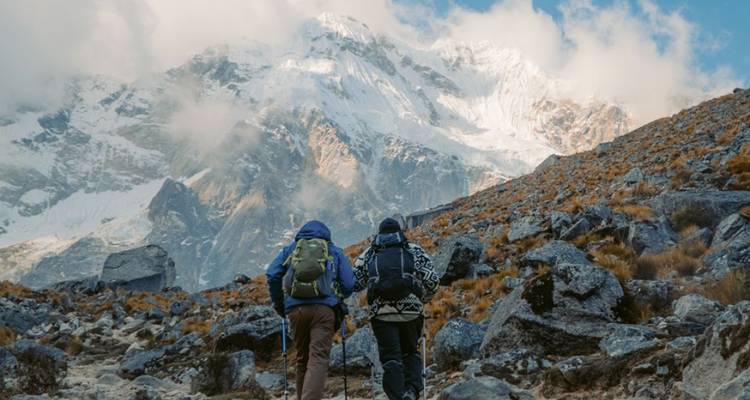 Dos excursionistas caminando hacia las montañas nevadas