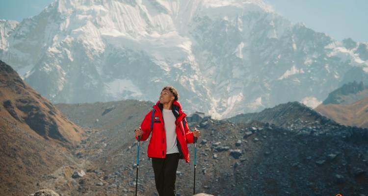 Excursionista con abrigo rojo y montañas al fondo.