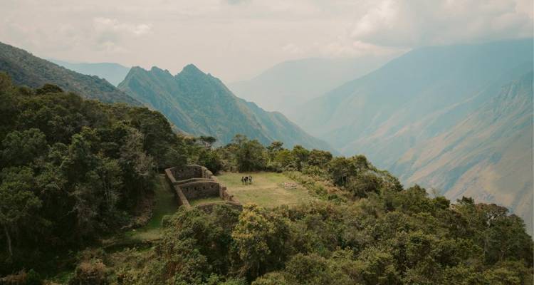 Paisaje montañoso con ruinas antiguas y montañas distantes.